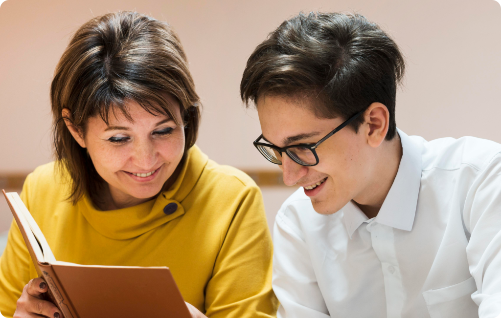 Parent and teenage son reading a book together