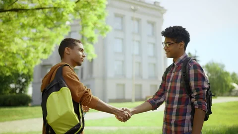 Two students shaking hands outside a campus building